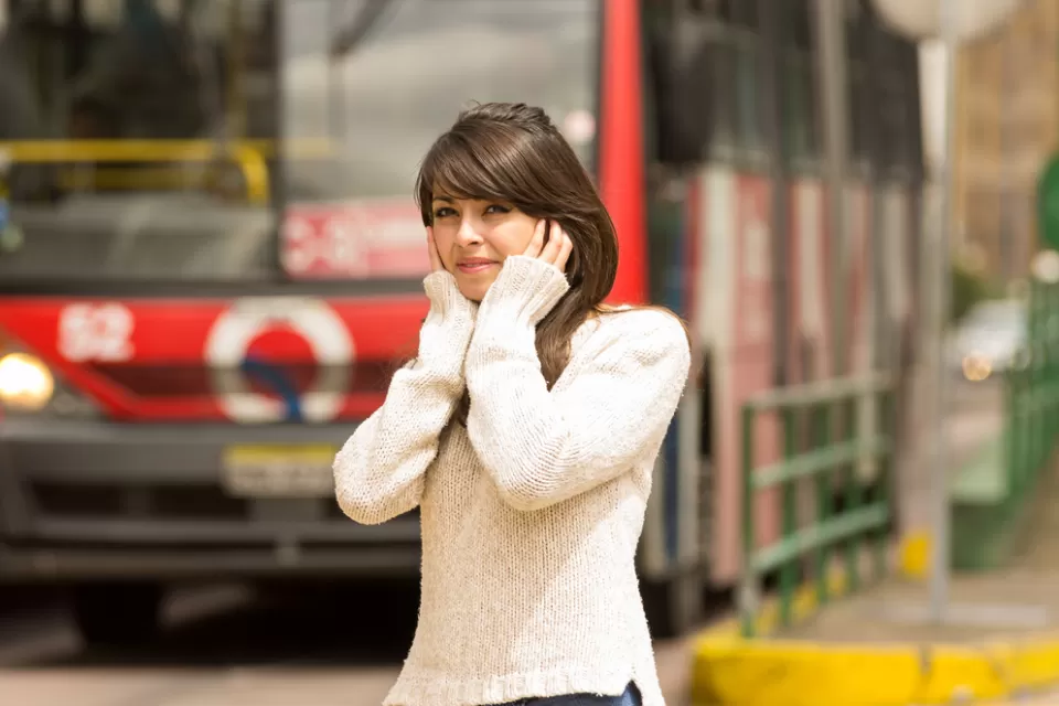 portrait of woman walking on the city street covering her ears